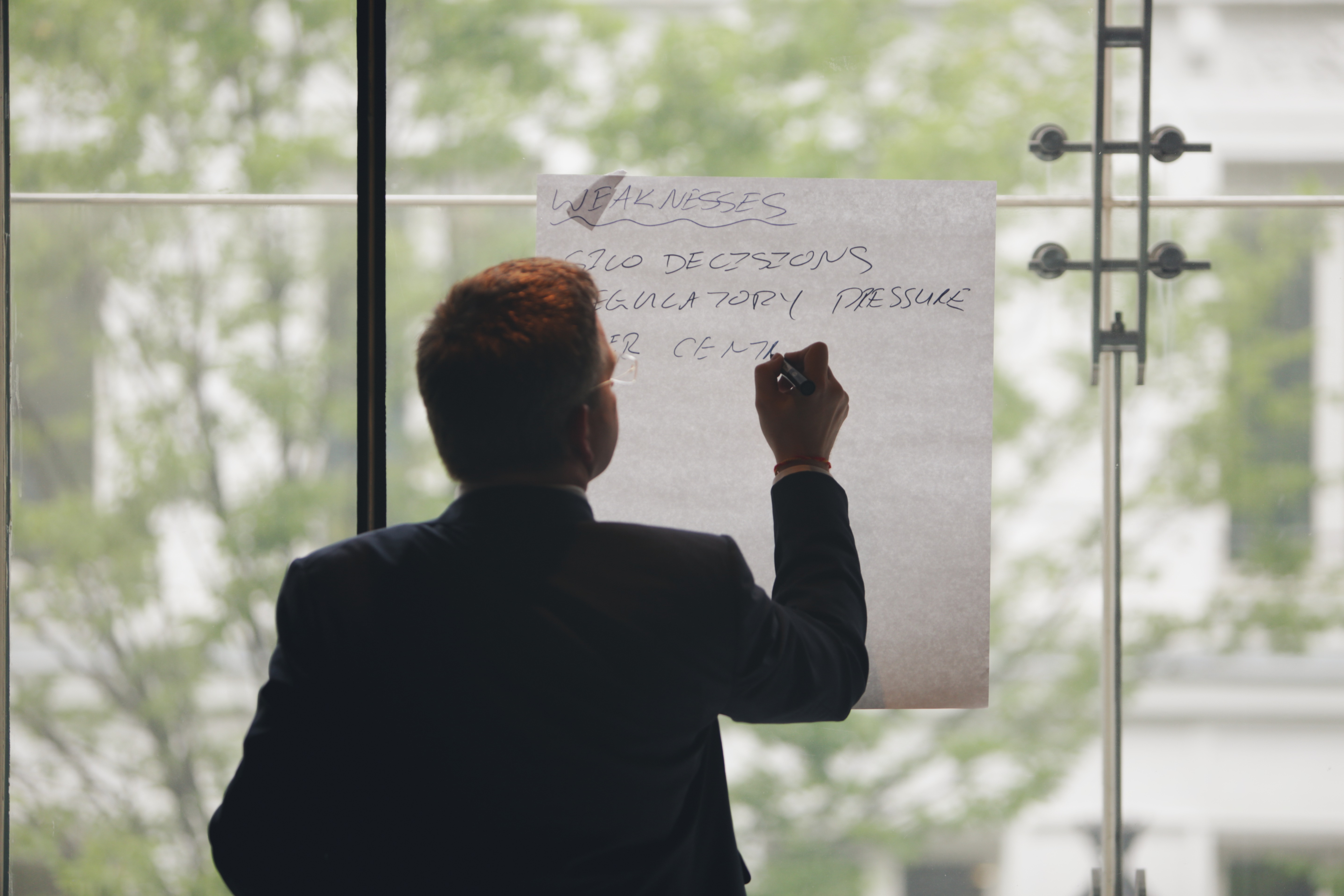 A man seen from the back taking notes on a paperboard